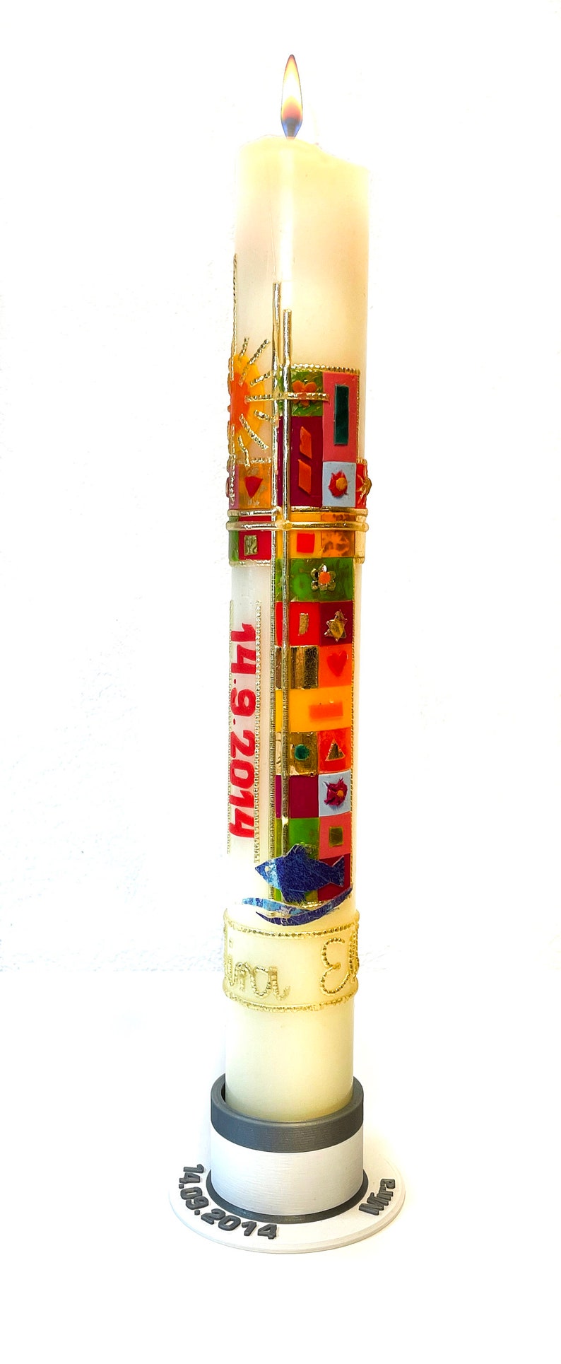 May include: A white candle with a gold and colorful design, the date "14.09.2014" and the word "Mira" on the base.
