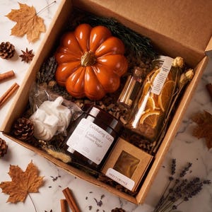 May include: A cardboard gift box containing an orange ceramic pumpkin, a jar of Cashmere and Brown Sugar exfoliating cubes, a glass bottle of dried orange slices labeled Pumpkin Spice, a small box labeled Sweet Orange, and a white pumpkin-shaped item.