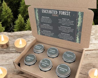 May include: A brown cardboard gift box containing six small round metal tins with labels reading Magical Woods, Castle Library, Enchantment Elixir, Dragon's Lair, The Enchanted Rose, and Whispering Winds, with a descriptive insert card.