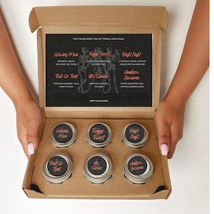 May include: A cardboard gift box containing six round metal tins with black labels featuring orange text. The labels are titled Glowing Moon, Foggy Forest, Fright Night, Trick Or Treat, 80s Slasher, and Headless Horsemen. An insert card lists scent notes.