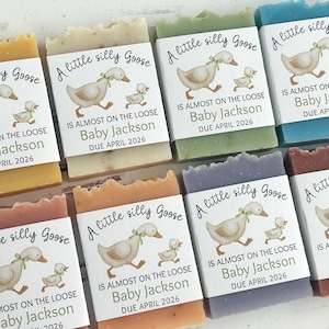 Puede incluir: Varias pastillas de jab&oacute;n de colores, cada una envuelta con una etiqueta con un dibujo de un ganso y un gansito. Las etiquetas dicen "A little silly Goose" y "Baby Jackson DUE APRIL 2026".