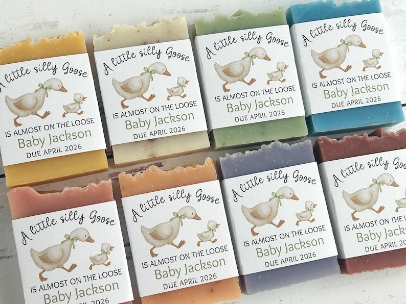 Puede incluir: Varias pastillas de jab&oacute;n de colores, cada una envuelta con una etiqueta con un dibujo de un ganso y un gansito. Las etiquetas dicen "A little silly Goose" y "Baby Jackson DUE APRIL 2026".