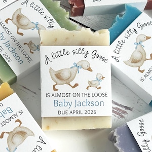 Puede incluir: Barras de jab&oacute;n hechas a mano con etiquetas que presentan una ilustraci&oacute;n de acuarela de un ganso y un gansito. Las etiquetas dicen "A little silly Goose" y "Is almost on the loose Baby Jackson Due April 2026". Los jabones son de varios colores.