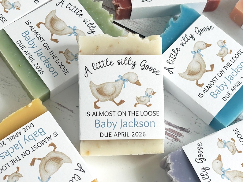 Puede incluir: Barras de jab&oacute;n hechas a mano con etiquetas que presentan una ilustraci&oacute;n de acuarela de un ganso y un gansito. Las etiquetas dicen "A little silly Goose" y "Is almost on the loose Baby Jackson Due April 2026". Los jabones son de varios colores.