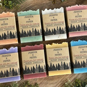 May include: Eight rectangular bars of soap in various colors including peach, green, white, pink, purple, maroon, yellow, and blue. Each bar is wrapped in a brown paper band printed with the text JESSICA & PETER, Thank you for coming!, 09.26.26, Catskill, NY.