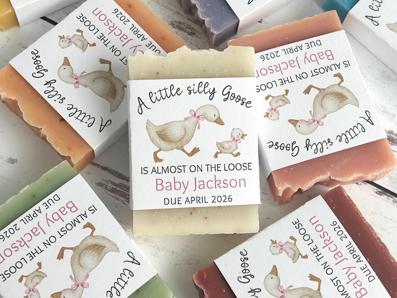 Puede incluir: Barras de jab&oacute;n de varios colores con etiquetas que presentan una ilustraci&oacute;n de acuarela de un ganso y un ganso. Las etiquetas dicen: "A little silly Goose, Is almost on the loose, Baby Jackson, Due April 2026."