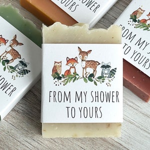Pode incluir: V&aacute;rias barras de sab&atilde;o com r&oacute;tulos brancos com ilustra&ccedil;&otilde;es de animais da floresta e o texto "FROM MY SHOWER TO YOURS". Os sabonetes s&atilde;o de v&aacute;rias cores, incluindo verde, castanho e bege.