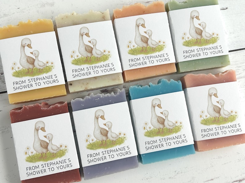 Puede incluir: Surtido de jabones hechos a mano en varios colores, cada uno envuelto con una etiqueta con una ilustraci&oacute;n de un ganso y un ganso. Las etiquetas dicen "FROM STEPHANIE'S SHOWER TO YOURS". Los jabones son de color amarillo, beige, naranja, verde, rojo, morado, azul y rosa.