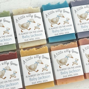 Puede incluir: Surtido de jabones hechos a mano en varios colores, cada uno con una etiqueta con un ganso de dibujos animados y el texto "A little silly Goose". Las etiquetas tambi&eacute;n incluyen el nombre "Baby Jackson" y la fecha de vencimiento "Abril 2026."