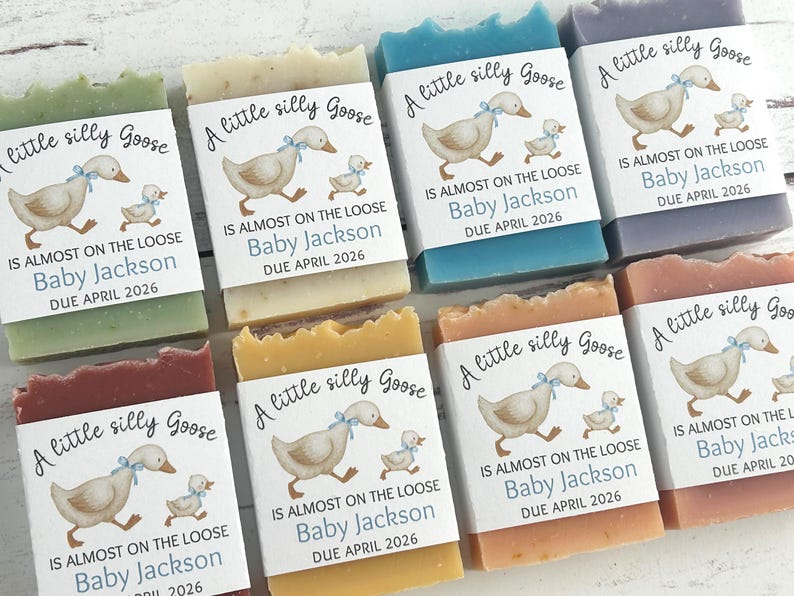 Puede incluir: Surtido de jabones hechos a mano en varios colores, cada uno con una etiqueta con un ganso de dibujos animados y el texto "A little silly Goose". Las etiquetas tambi&eacute;n incluyen el nombre "Baby Jackson" y la fecha de vencimiento "Abril 2026."