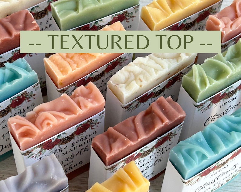 Puede incluir: Una variedad de jabones coloridos y texturizados en cajas decorativas. Los jabones son de varios colores, incluyendo rosa, azul, verde y amarillo. El texto "-- TEXTURED TOP --" se muestra en la imagen. Las cajas tienen patrones florales y texto.