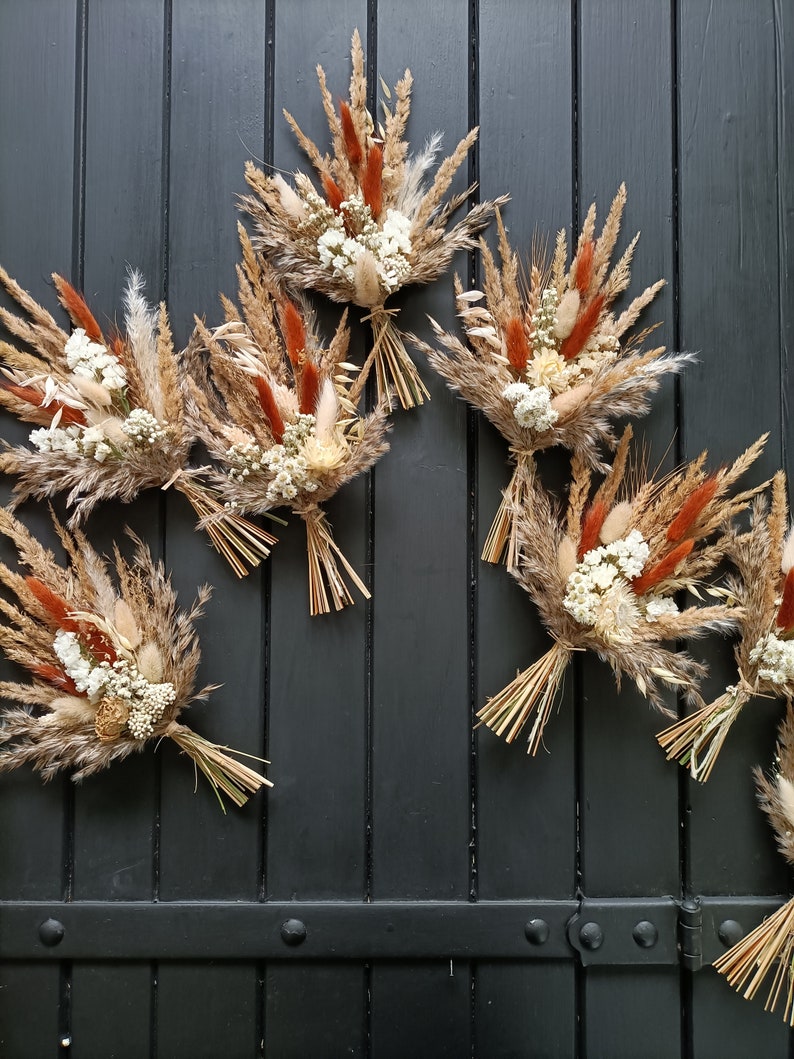 Pu&ograve; includere: Diversi bouquet di fiori secchi con grano, erba della pampa e piccoli fiori bianchi. I bouquet presentano una palette di colori naturali con accenti ruggine e beige. Gli steli sono legati con paglia.
