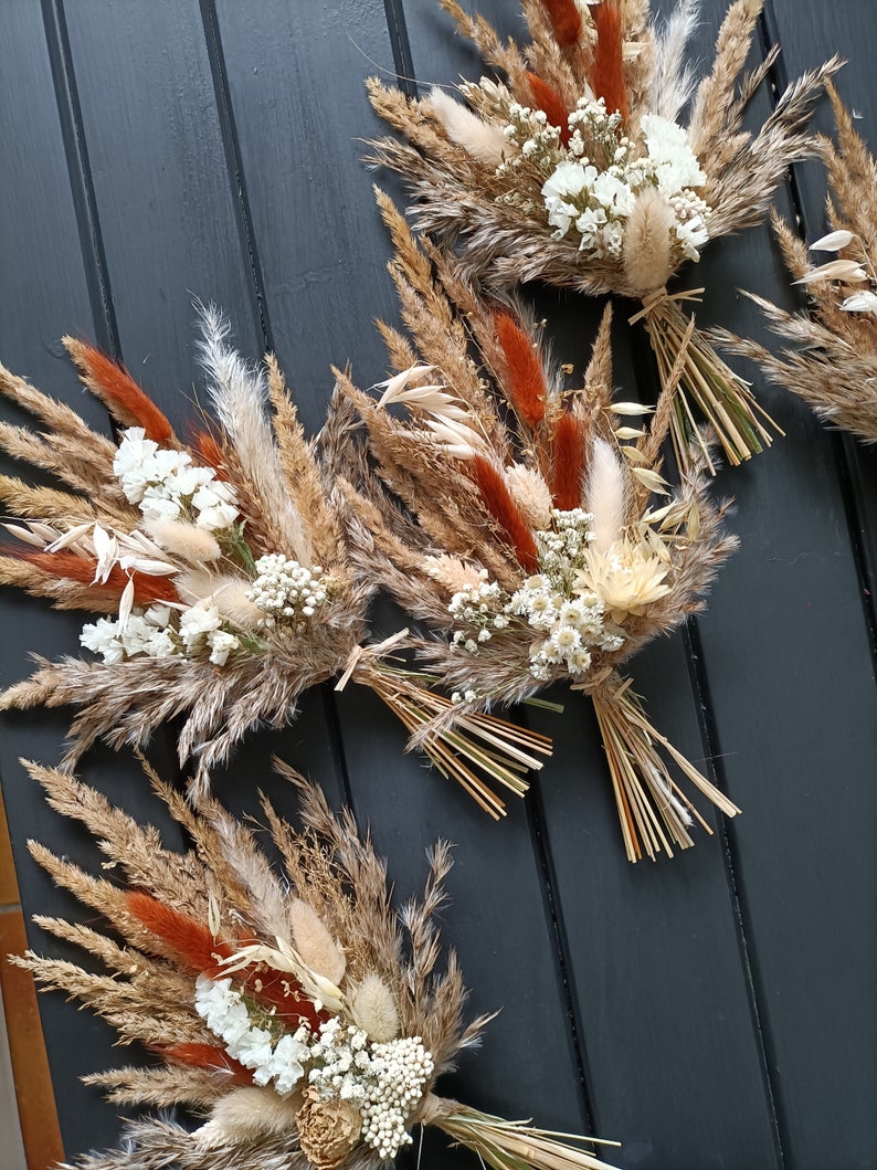 Pu&ograve; includere: Diversi bouquet di fiori secchi con un mix di erbe e fiori beige, marroni e color ruggine. Ogni bouquet &egrave; legato con spago naturale e presenta piccoli fiori bianchi. I bouquet sono disposti su una superficie grigio scuro.