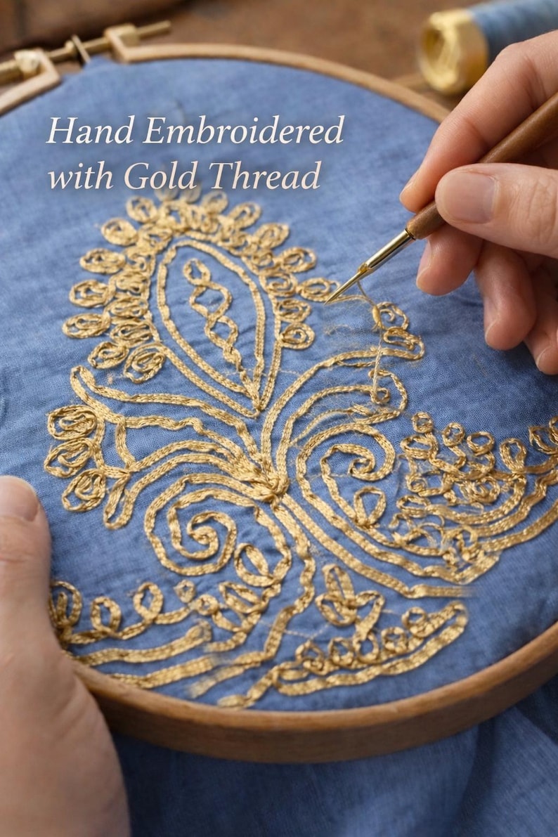 May include: Hand-embroidered design with gold thread on blue fabric, held in a wooden embroidery hoop. The text "Hand Embroidered with Gold Thread" is visible. The design features floral and scroll patterns.