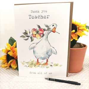 May include: A greetings card featuring a watercolour illustration of a goose holding apples. The text on the card reads "Thank you Teacher" and "from all of us". The card is set against a background with sunflowers.
