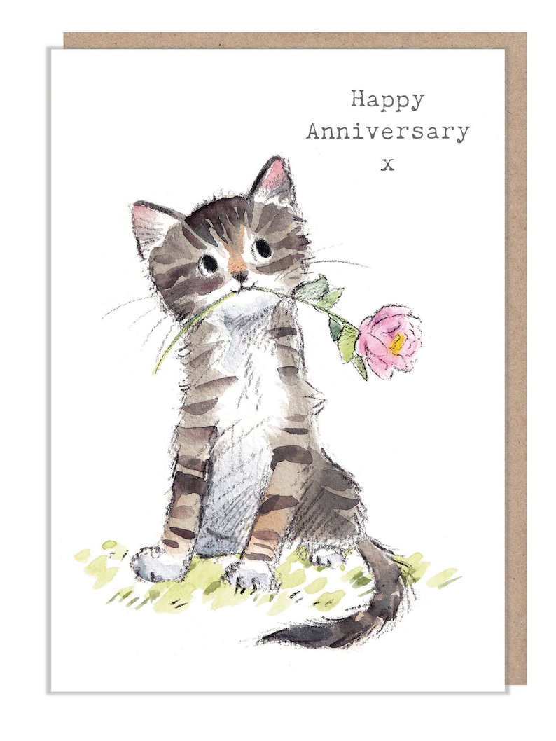 May include: A watercolor illustration of a cute tabby cat holding a pink flower in its mouth. The text "Happy Anniversary" and an "x" are written above the cat.