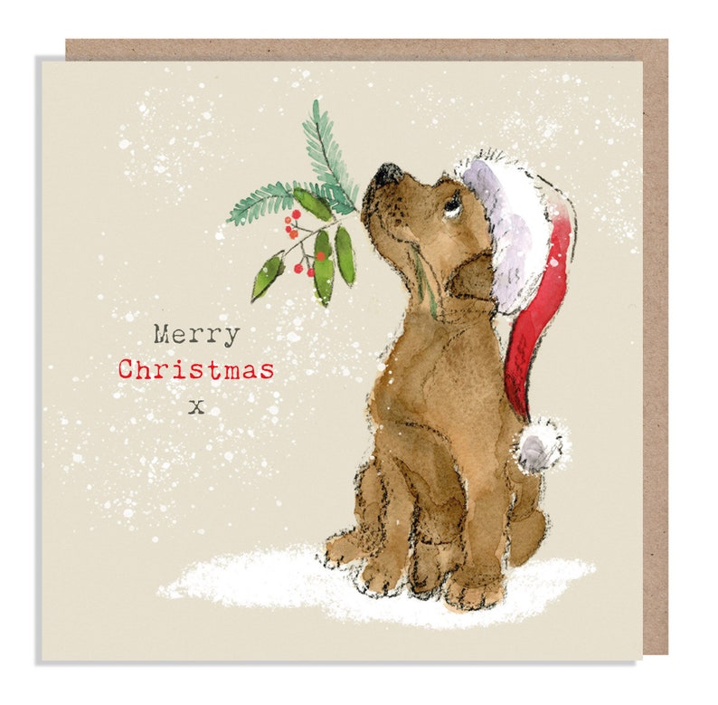 May include: A Christmas card featuring a brown dog wearing a red Santa hat and looking up at a sprig of holly with red berries. The card has a white background with a light brown border and the text "Merry Christmas" in red.