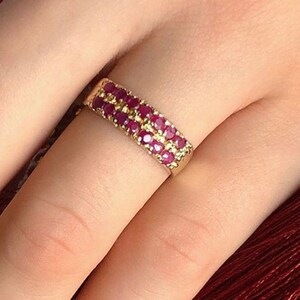 May include: A gold band ring with two rows of small, red ruby stones.