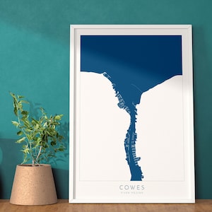 Può includere: Una stampa incorniciata bianca di una mappa blu di Cowes, River Medina. La mappa è un contorno stilizzato della città e dell'acqua circostante.