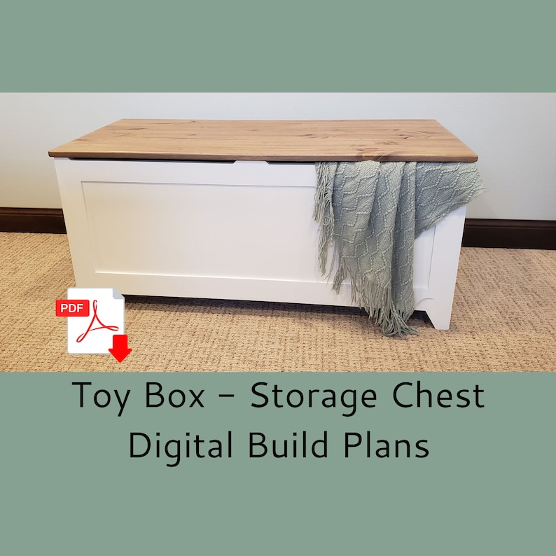May include: White toy box with a wooden lid and a light blue blanket draped over the side. The text "Toy Box - Storage Chest Digital Build Plans" is below the box. A PDF icon is in the top left corner.