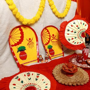 Puede incluir: Una colección de artículos coloridos hechos a mano, que incluyen abanicos, bandejas pintadas y cerámica decorativa. Los artículos presentan diseños rojos, amarillos y blancos, con patrones tradicionales. Una guirnalda amarilla añade un toque festivo.