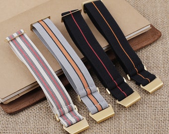 May include: Four different watch straps with gold buckles. The straps are made of elastic material with striped patterns in black, red, orange, and gray.