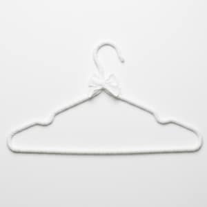 May include: A white, padded clothing hanger with a small bow at the hook. The hanger is designed to hold garments and is made of a soft, textured material. The bow adds a decorative touch to the hanger.