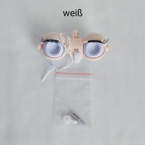 Könnte beinhalten: Ein Paar weiße Puppenaugen mit schwarzen Wimpern und einer weißen Schnur. Die Augen befinden sich in einem Plastikhalter. Ein kleiner Plastikbeutel mit einer Schraube und einer Unterlegscheibe ist im Lieferumfang enthalten.