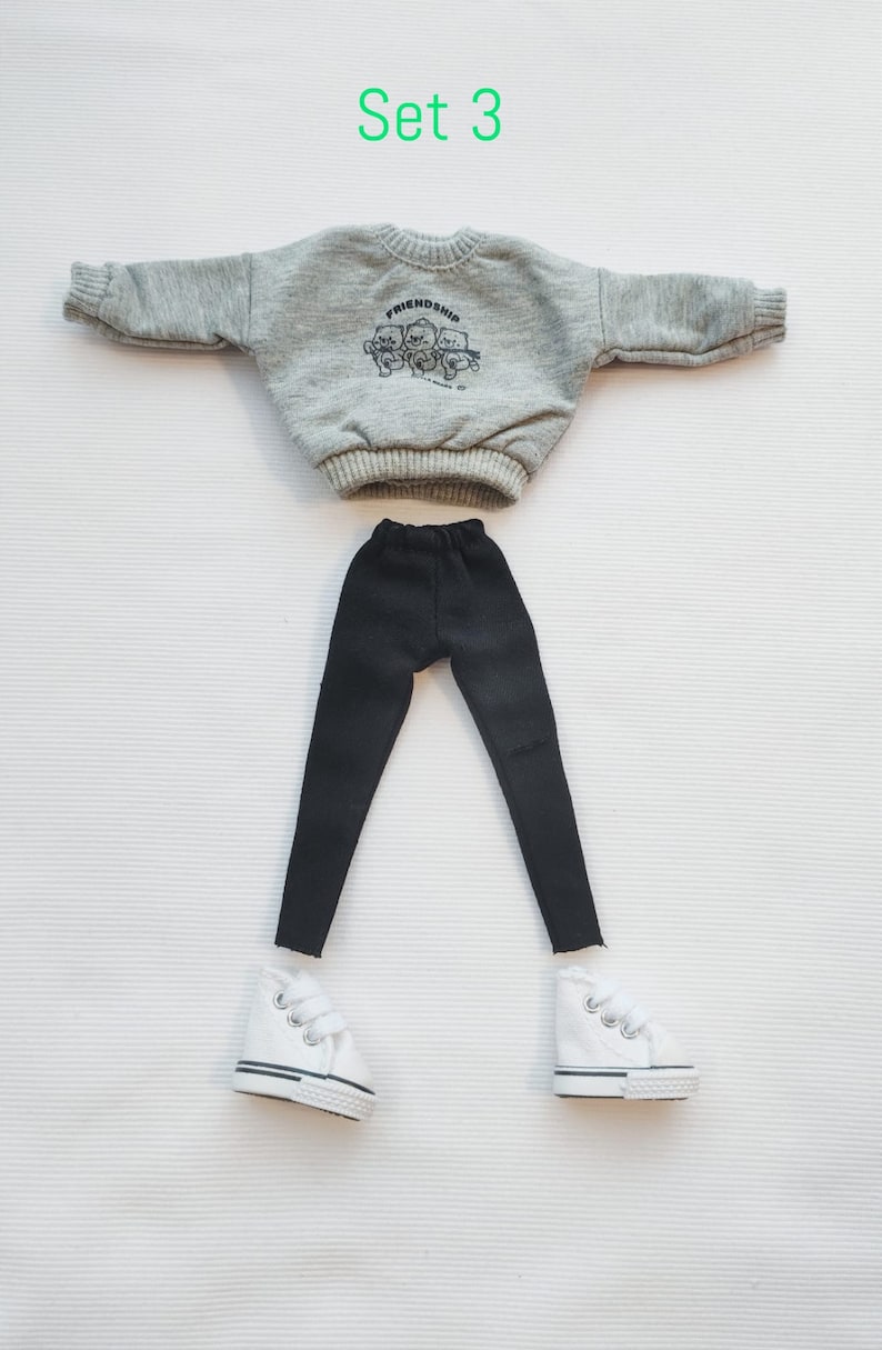 May include: A doll outfit set with a grey sweatshirt with the word "Friendship" printed on it, black leggings, and white sneakers.