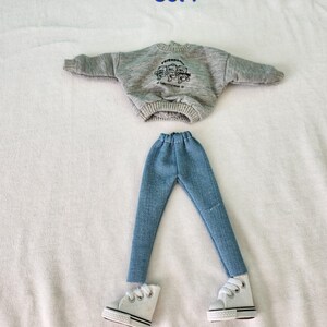 May include: A gray sweatshirt with the text "FRIENDS" and a graphic of three bears. The sweatshirt is paired with blue jeans and white sneakers. The text "Set 7" is written above the outfit.