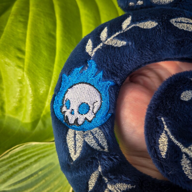 Op de afbeelding: Donkerblauwe pluche hoofdband met geborduurde zilveren bladeren en een blauw vlammenontwerp met een witte schedel. De hoofdband is zacht en pluche, perfect voor cosplay of dagelijks gebruik.