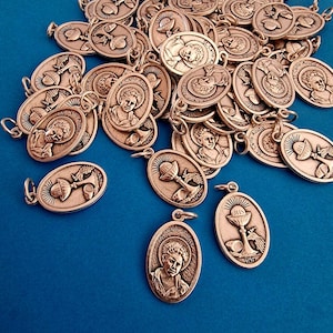 Könnte beinhalten: Eine Ansammlung bronzefarbener ovaler Anhänger mit religiösen Motiven. Die Anhänger zeigen St. Carlo Acutis und andere religiöse Symbole. Jeder Anhänger hat eine kleine Schlaufe zum Befestigen.