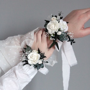White floral wrist corsage for bridesmaid, matching wedding set with boutonniere.