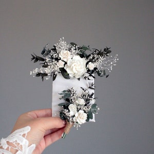 Matching white and greenery boutonnieres for groom and groomsmen, rustic wedding style.