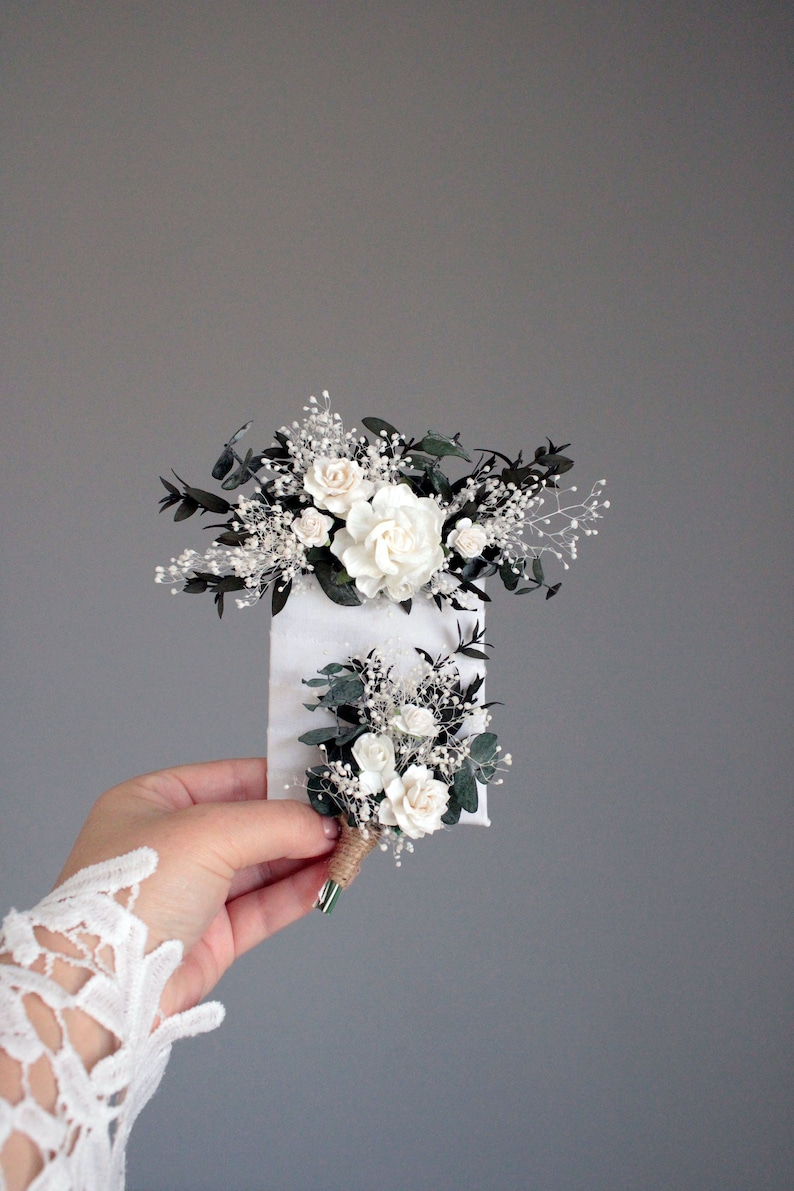 Matching white and greenery boutonnieres for groom and groomsmen, rustic wedding style.