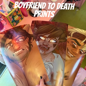 May include: Three art prints featuring male characters with intense expressions. The prints have a golden skin tone and detailed illustrations. The text "BOYFRIEND TO DEATH PRINTS" is displayed in white, stylized font.