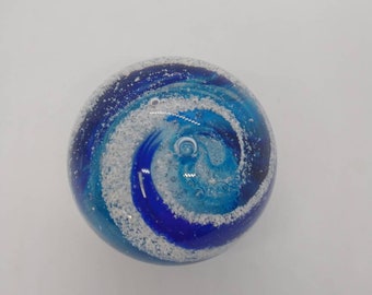 May include: A blue and white glass orb with a swirling pattern. The orb is filled with small white bubbles.