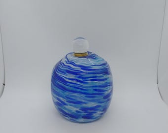 May include: A decorative glass bottle with a round body and a clear, spherical stopper. The bottle features a blue and white swirled pattern, creating a water-like effect. The stopper is attached with a gold-coloured band.