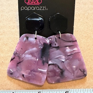 May include: A pair of dangle earrings with a black hexagonal top and a marbled pink and black rectangular bottom. The earrings are attached to a black card with the word "paparazzi" printed on it.