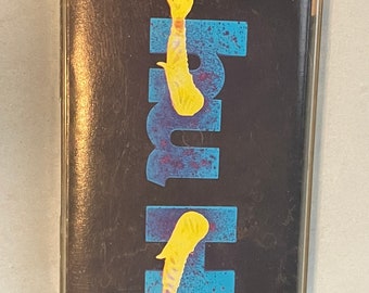 May include: A cassette tape with a black background and a blue and white design. The design features two yellow arms with hands reaching up. The text "HIGH" is printed in white on the blue and white design.