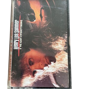 Puede incluir: Una cinta de casete con una etiqueta roja y blanca. La etiqueta dice "Henry Lee Summer" y "I've Got Everything". La imagen en la cinta es un primer plano de la cara de una persona con cabello largo y rubio.