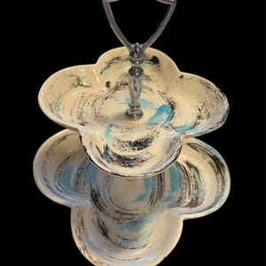 May include: Two-tiered serving tray with a silver handle. The tray is white with blue and black swirling patterns.