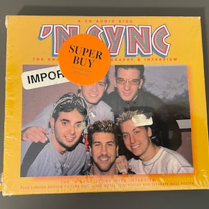 Pode incluir: Uma biografia de áudio em CD da boy band 'N Sync. A capa apresenta uma foto de grupo dos cinco membros, com um adesivo 'Super Buy' no canto superior esquerdo. O texto 'The 'N Sync Story with Interview' está impresso na parte inferior da capa. O CD inclui um disco de imagem de edição limitada, notas de capa, um mini pôster e um pôster de parede separado.