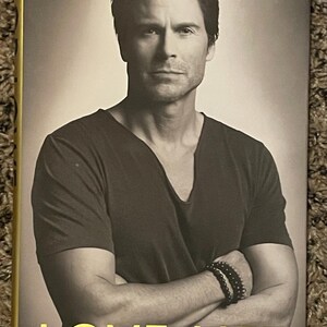 May include: A black and white photograph of a man wearing a black v-neck t-shirt. The man is looking at the camera with a serious expression. The book cover has the text "LOVE LIFE" in yellow lettering.