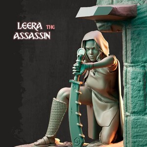 May include: A detailed sculpture of Leera the Assassin, kneeling and holding a large sword. The figure is clad in a hooded cloak and textured leg armor. The text "Leera the Assassin" is displayed above the figure.