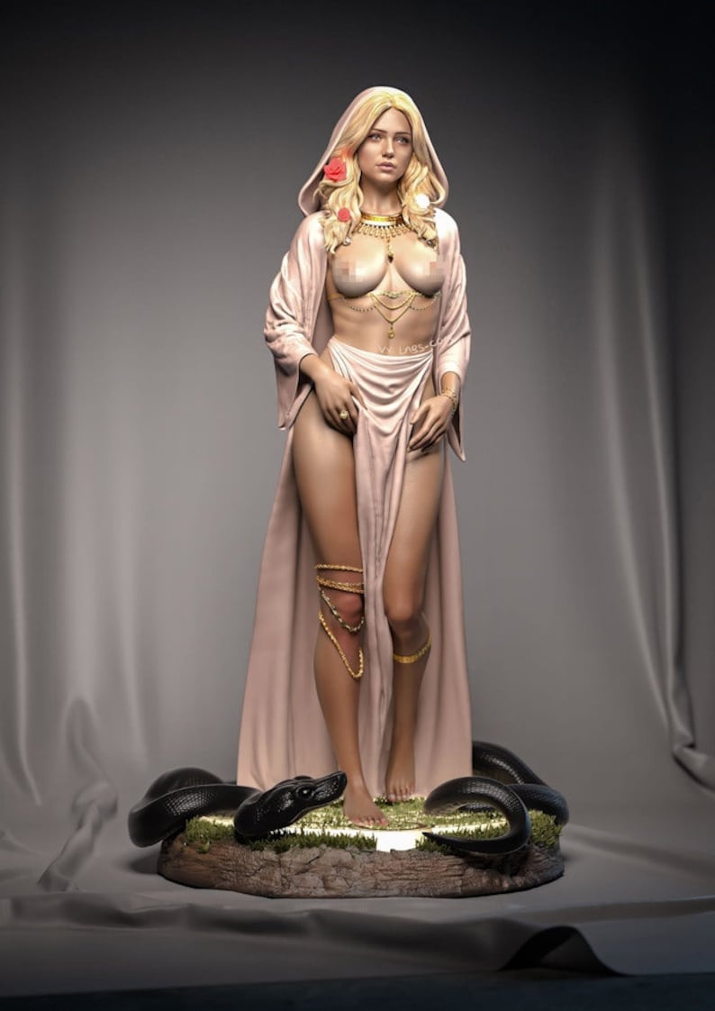 May include: A statue of a woman with long blonde hair, wearing a light pink robe and gold jewelry. The statue is standing on a base with a black snake. The woman has a serene expression.