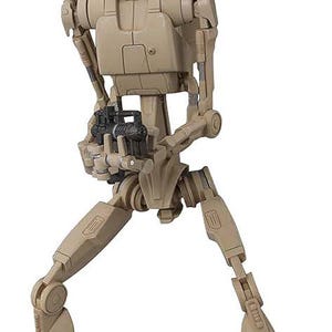 Könnte beinhalten: Eine beige und braune, bewegliche Actionfigur eines Star Wars Kampf-Droiden mit einem Blaster in den Händen.