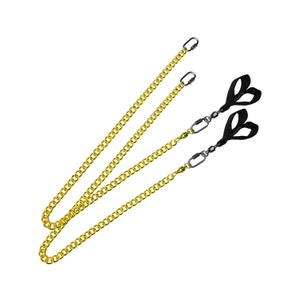 May include: Three gold chains with black straps and silver clips. The chains are linked together and are hanging on a white background.