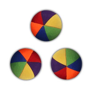 Può includere: Tre palle di tessuto multicolori con un design a sei pannelli. Ogni palla ha una disposizione di colori diversa di rosso, arancione, giallo, verde, blu e viola.