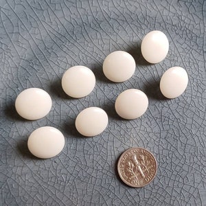 May include: Eight white round buttons on a gray textured surface. A US dime is included for scale.